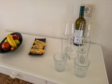 Hotel room amenities: wine, fruit, snacks, and glasses. clipart