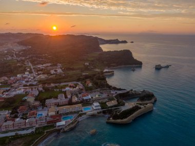 Sahil kasabasının günbatımı hava manzarası. Altın saat ışığı binaları ve denizi aydınlatıyor.