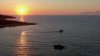 Korfu Yunancası 'nda gün batımına doğru bir balıkçı teknesini takip eden hava aracı