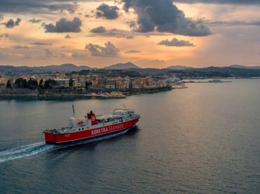 Kırmızı ve beyaz feribot gün batımında bir sahil kasabasından geçiyor..