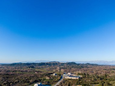 Açık mavi gökyüzünün altındaki kırsal bir arazinin havadan görünüşü.