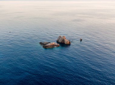 Kayalık çıkıntılı sakin deniz manzarası ve durgun mavi su.
