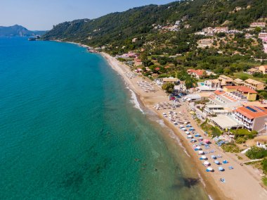 Yunanistan 'ın Korfu adasındaki Agios Gordios egzotik plajı. Agios Gordios plajı, Korfu adası, Yunanistan. Agios Gordios plajının panoramik manzarası, kumlu deniz kıyıları, plaj şemsiyeleri ve şezlonglar..