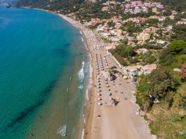 Yunanistan 'ın Korfu adasındaki Agios Gordios egzotik plajı. Agios Gordios plajı, Korfu adası, Yunanistan. Agios Gordios plajının panoramik manzarası, kumlu deniz kıyıları, plaj şemsiyeleri ve şezlonglar..