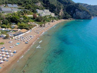 Agios Gordios exotic beach in Corfu island,Greece. Agios Gordios beach, Corfu island, Greece. Panoramic view of the Agios Gordios beach, sandy seashore with beach umbrellas and deck chairs. clipart