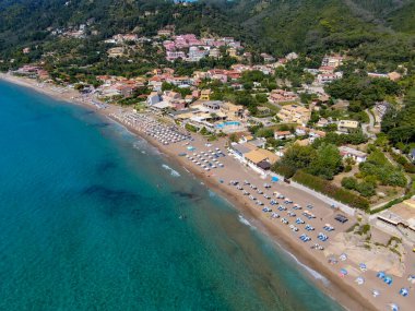 Yunanistan 'ın Korfu adasındaki Agios Gordios egzotik plajı. Agios Gordios plajı, Korfu adası, Yunanistan. Agios Gordios plajının panoramik manzarası, kumlu deniz kıyıları, plaj şemsiyeleri ve şezlonglar..