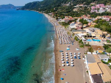 Yunanistan 'ın Korfu adasındaki Agios Gordios egzotik plajı. Agios Gordios plajı, Korfu adası, Yunanistan. Agios Gordios plajının panoramik manzarası, kumlu deniz kıyıları, plaj şemsiyeleri ve şezlonglar..