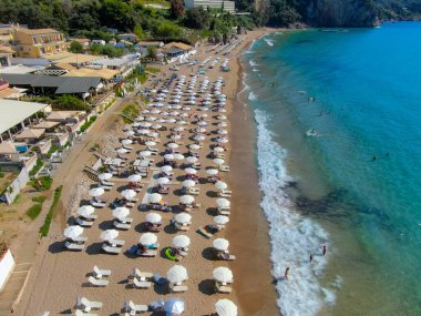 Agios Gordios exotic beach in Corfu island,Greece. Agios Gordios beach, Corfu island, Greece. Panoramic view of the Agios Gordios beach, sandy seashore with beach umbrellas and deck chairs. clipart