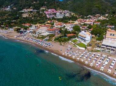 Yunanistan 'ın Korfu adasındaki Agios Gordios egzotik plajı. Agios Gordios plajı, Korfu adası, Yunanistan. Agios Gordios plajının panoramik manzarası, kumlu deniz kıyıları, plaj şemsiyeleri ve şezlonglar..