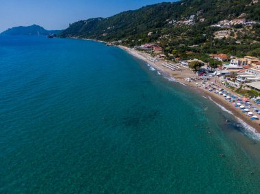 Yunanistan 'ın Korfu adasındaki Agios Gordios egzotik plajı. Agios Gordios plajı, Korfu adası, Yunanistan. Agios Gordios plajının panoramik manzarası, kumlu deniz kıyıları, plaj şemsiyeleri ve şezlonglar..