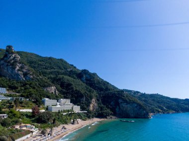 Yunanistan 'ın Korfu adasındaki Agios Gordios egzotik plajı. Agios Gordios plajı, Korfu adası, Yunanistan. Agios Gordios plajının panoramik manzarası, kumlu deniz kıyıları, plaj şemsiyeleri ve şezlonglar..