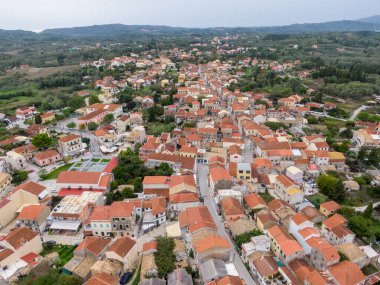Yeşil tepelerin arasına kurulmuş büyüleyici bir köyün havadan görünüşü.
