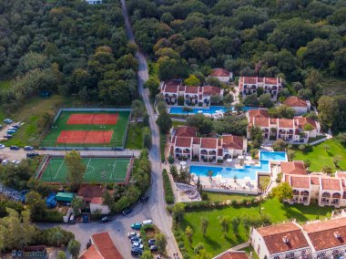 Havuz ve spor sahaları ile tesis kompleksinin havadan görünümü.