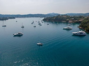 Lüks yatlar ve yelkenliler yemyeşil yemyeşil bir körfezde demirlediler..