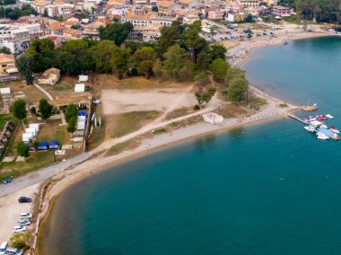 Sahil kenti hava manzarası: sahil, turkuaz su, tekne ve binalar.