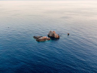 Kayalık çıkıntılı sakin deniz manzarası ve durgun mavi su.