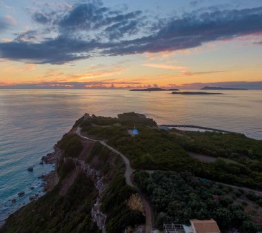 Kıyı günbatımı manzaralı, uzakta küçük bir şapel ve adalar var..