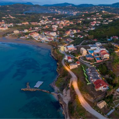Alacakaranlıkta sahil kasabası, hava manzaralı. Huzurlu sahil, okyanus ve köy ışıkları.