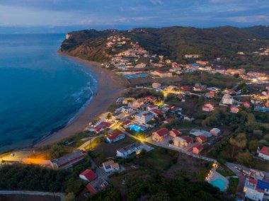 Alacakaranlıkta sahil kasabası, hava manzaralı. Huzurlu sahil, okyanus ve yamaçtaki evler.
