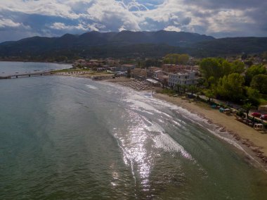 Sahildeki sahil sahnesinde arka planda dağlar var.