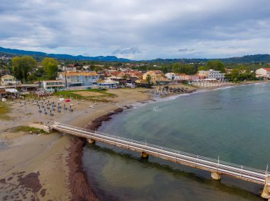 Kumsalı, rıhtımı ve bulutlu gökyüzünün altında sakin bir denizi olan kıyı kasabası..