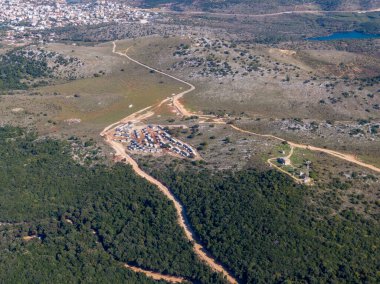 Dağlık, ormanlı bir araziye kurulmuş uzak yerleşim alanının havadan görünüşü.