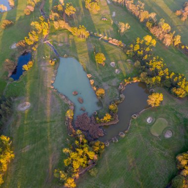 Göletli ve yemyeşil yemyeşil golf sahasının havadan görünüşü.