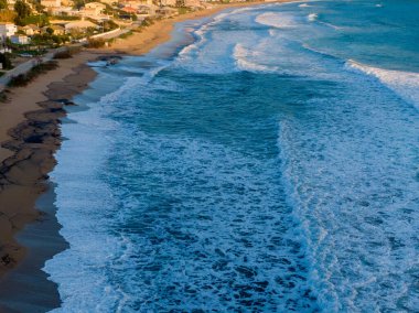 Kıyı evleri yakınlarındaki kumlu kıyılara okyanus dalgaları çarpıyor.