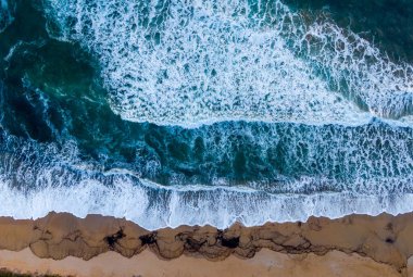 Okyanus dalgalarının kumlu kumsala düşüşünün hava görüntüsü..