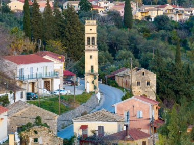 Çan kulesi, evler ve dolambaçlı yollarla köy sahnesi.