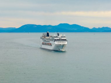 Sakin okyanusta dağlara doğru yelken açan bir gemi.
