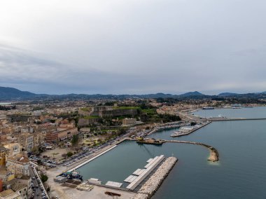Kalesi ve marinası olan sahil kenti limanı. Arka planda tekneler, binalar ve dağlar var..