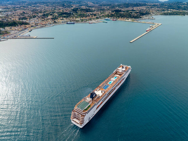 Круизный корабль приближается к прибрежной городской гавани.