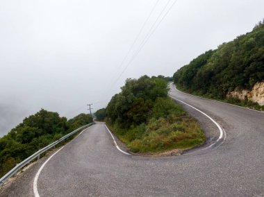 Sisli bir günde yemyeşil tepelerde dolambaçlı bir yol.