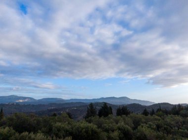 Parçalı bulutlu bir gökyüzünün altındaki sakin dağ manzarası.