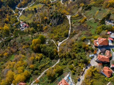 Evleri ve dolambaçlı yolları olan sonbahar manzarası.