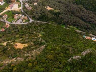Bereketli yeşil tepeler ve yerleşim alanlarında dolambaçlı yolların havadan görünüşü.
