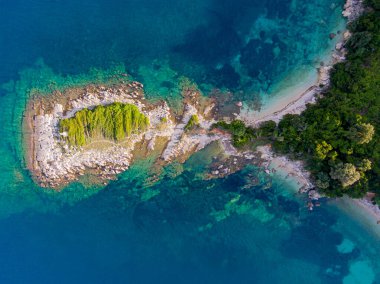 Turkuaz sudaki küçük bir adanın havadan görünüşü.