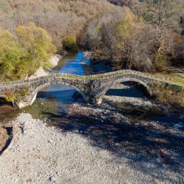 Aerial drone view of the traditional stone Mylos Bridge in Epirus, Greece in Autumn clipart