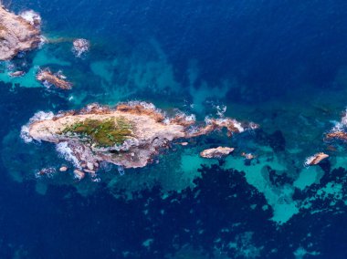 Turkuaz okyanus sularındaki küçük bir adanın havadan görünüşü.