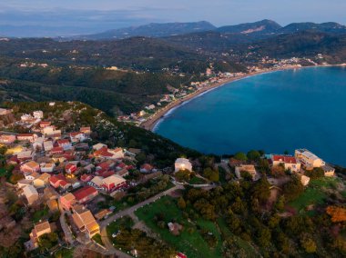 Gün batımında kıyı köyü, deniz ve dağlara bakıyor..