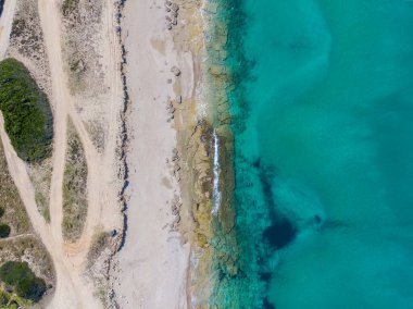 Turkuaz sularla buluşan el değmemiş bir sahil manzarası. Rocky kıyı şeridi ve kumlu sahil.