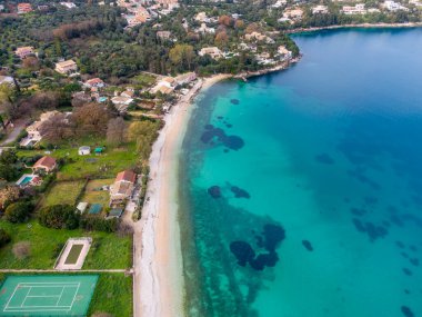 Gözlerden uzak bir sahil manzarası, turkuaz su ve kıyı evleri..