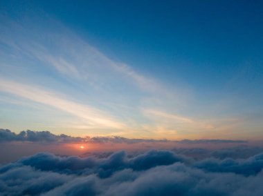 Bulutların üzerinde gün batımı, gökyüzünü canlı renklerle boyuyor..