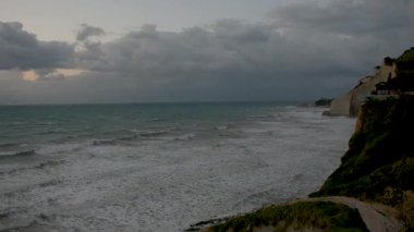 Kıyı kayalıkları bulutlu bir gökyüzünün altında çalkantılı bir denizle karşılaşır. loggas Beach Corfu, Yunanistan