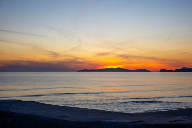 Okyanusun üzerinde altın ufukta. Ufuktaki sıcak güneş ışığı ve yumuşak dalgalar yavaşça içeri giriyor..