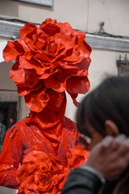 Korfu, korfu, Yunanistan. 10 Mart 2024: Kırmızı gül kostümü giymiş bir sokak sanatçısı