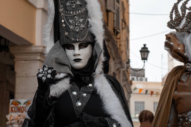 Festivalde ya da sokak performansında siyah beyaz kostüm ve maske giyen kişi.