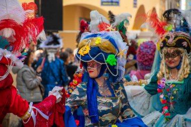 Şenlikli figürler ayrıntılı karnaval kostümleri giyip, detaylarla parıldıyor ve bir geçit töreninde canlı renkler sergiliyor..