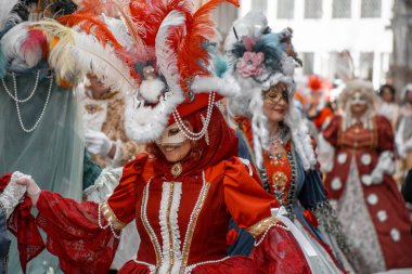 Özenle hazırlanmış kostümlerle süslenmiş insanlar açık havada maskeler ve tüylerle kutlama yapıyorlar..